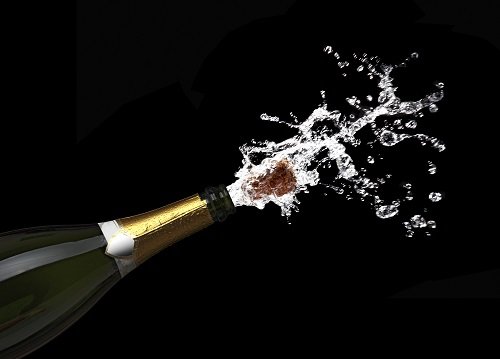 champagne bottle popping its cork with champagne splashing out